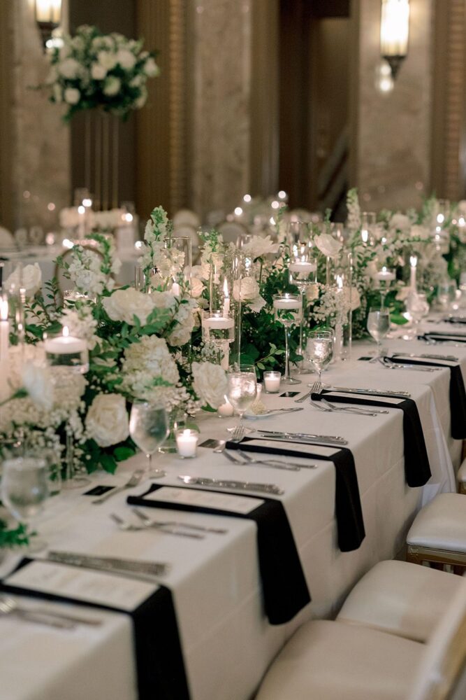 White wedding flowers and candlelight lining a long reception table