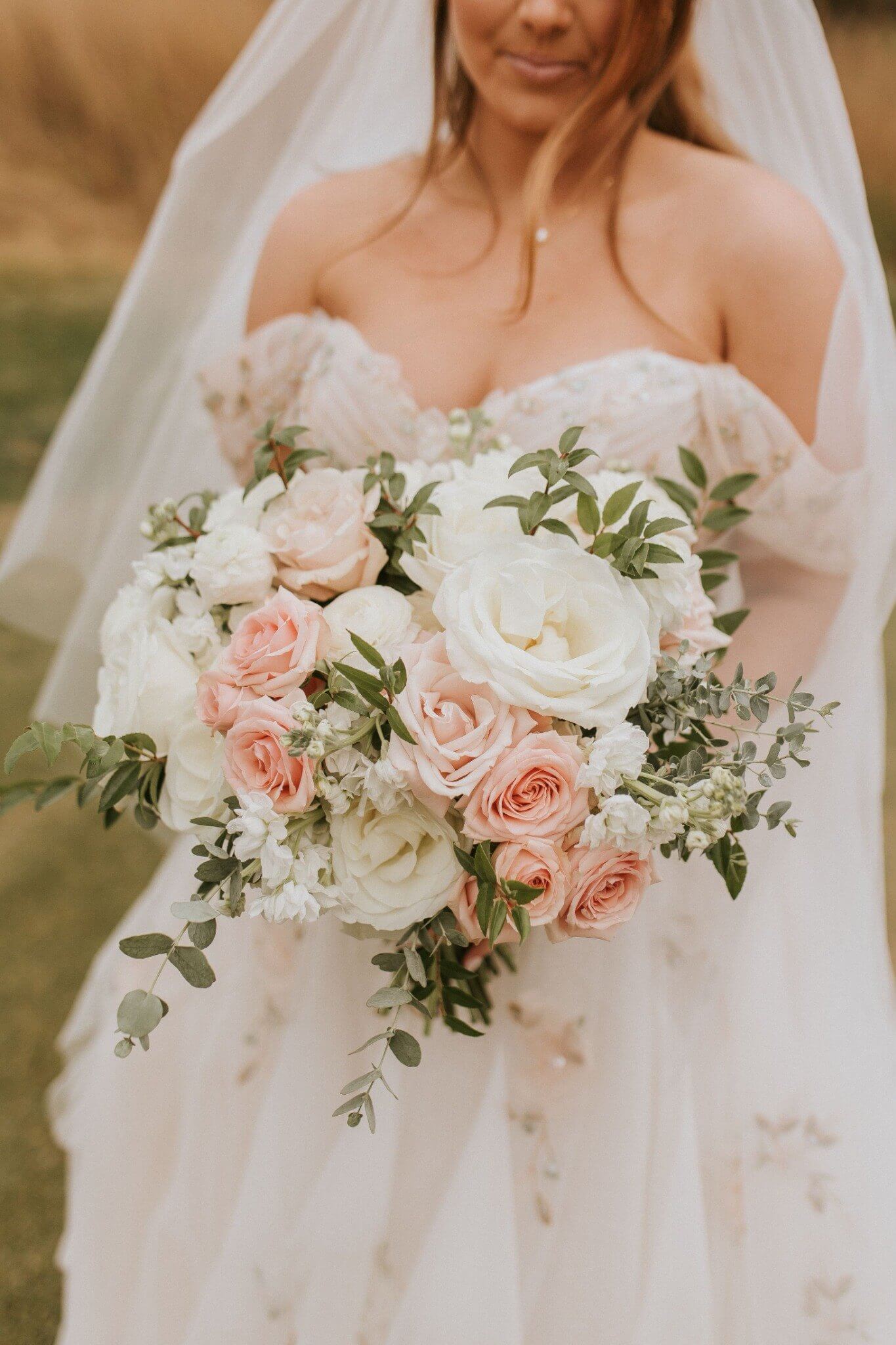 Blush and white bridal bouquet with roses, ranunculus, and eucalyptus at Whitmoor Country Club