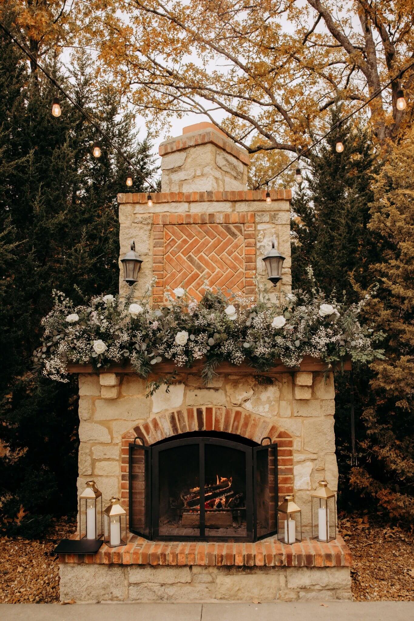 White roses, baby’s breath, eucalyptus, and greenery decorating the outdoor stone fireplace at Silver Oaks Chateau