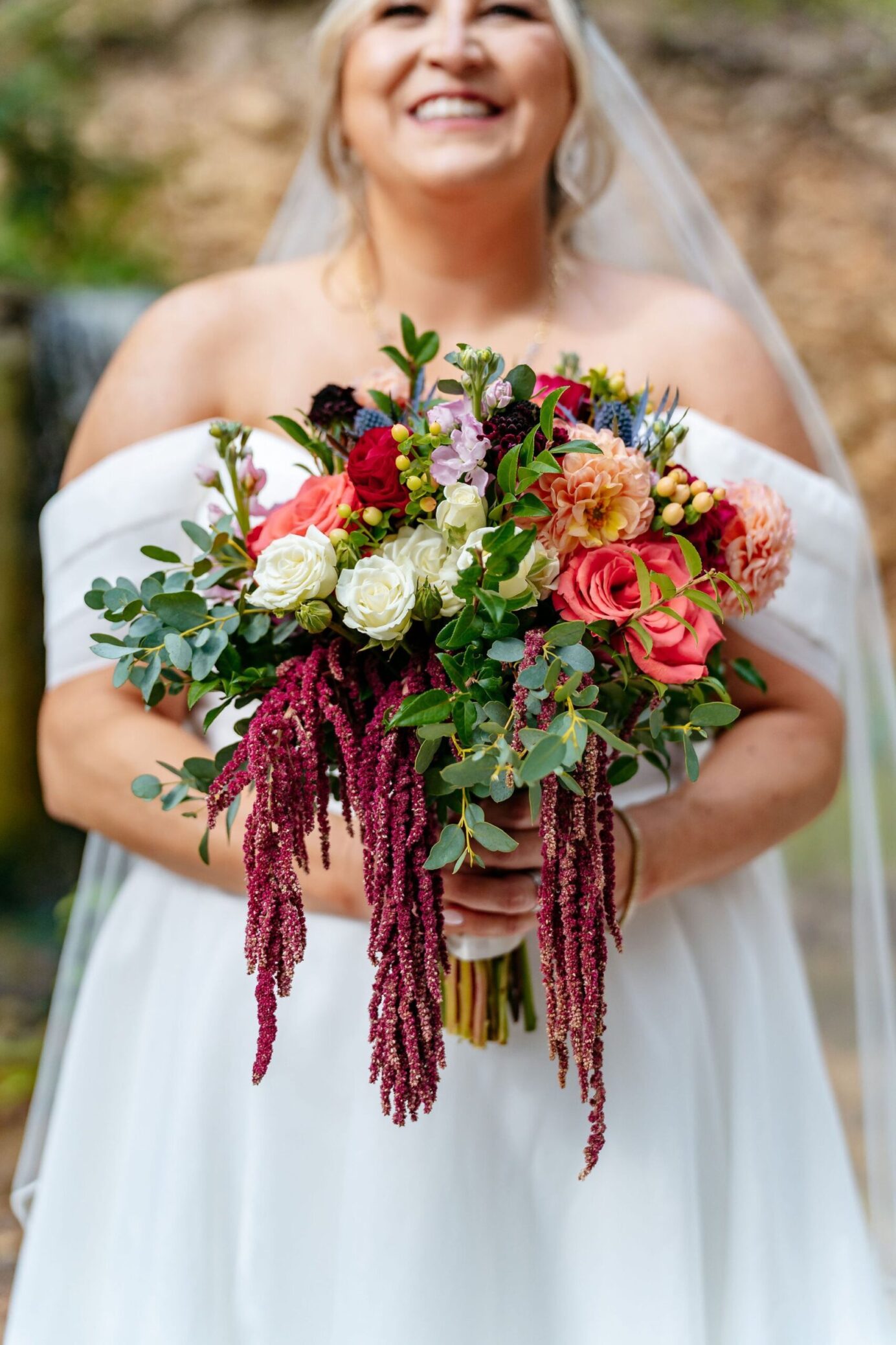 Bride with a bouquet featuring red hanging amaranthus