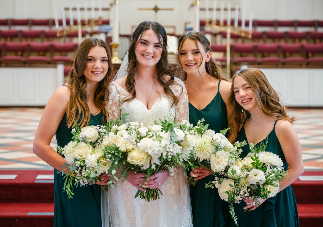 Bride and bridesmaids carrying coordinated white wedding bouquets