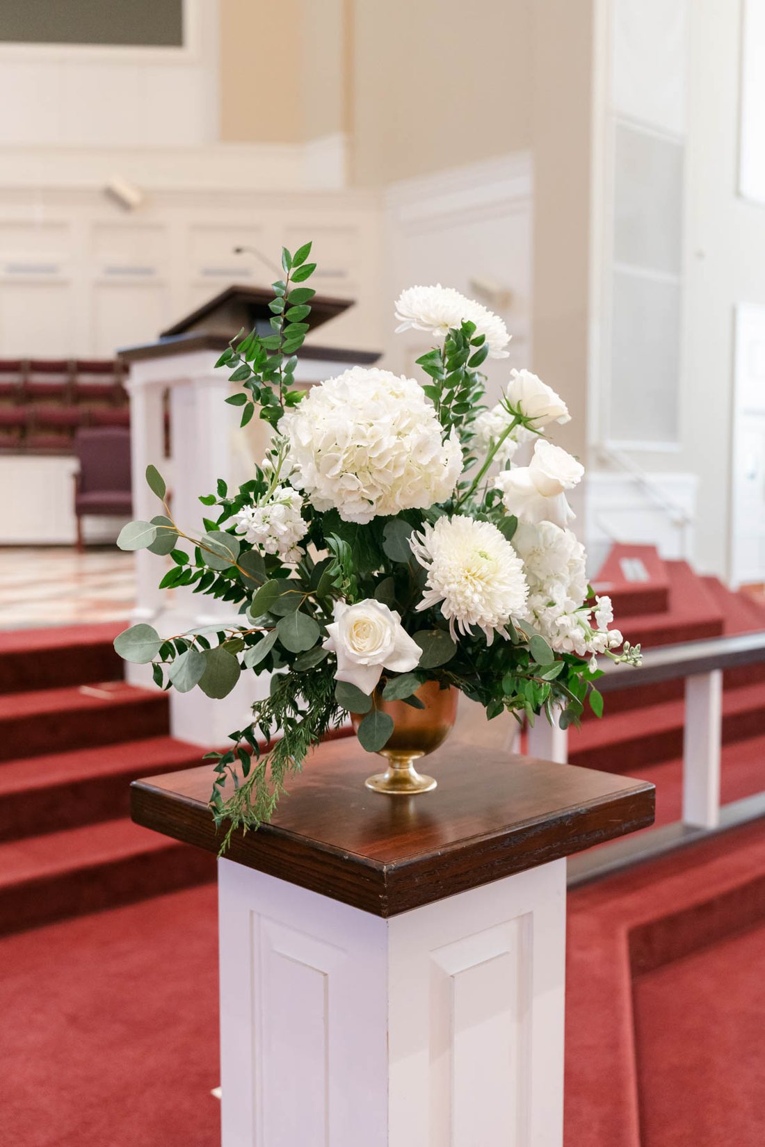 White floral arrangement on a pedestal at the church altar