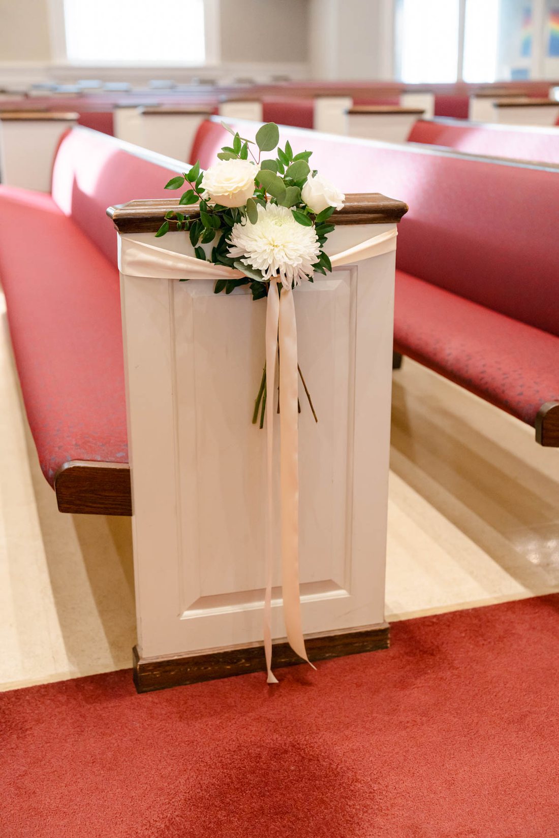 White winter flower arrangement decorating a church pew