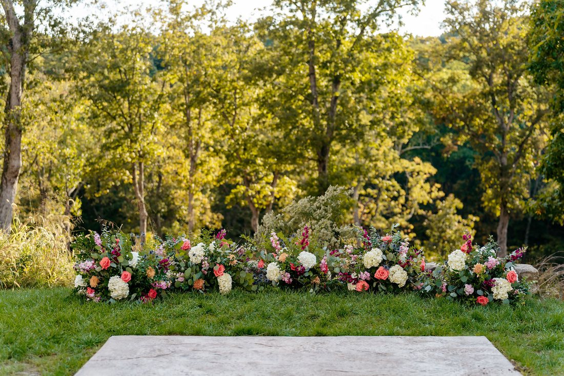 Ground flower arch used as an outdoor wedding ceremony backdrop