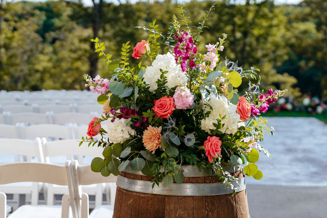 Wedding ceremony barrel arrangement with rust, white, and blue flowers