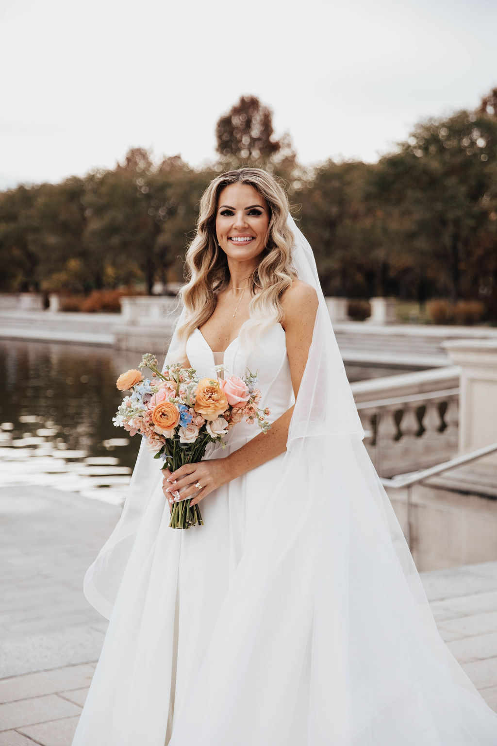 Bride and groom with a peach, coral pink, light blue and white wedding bouquet