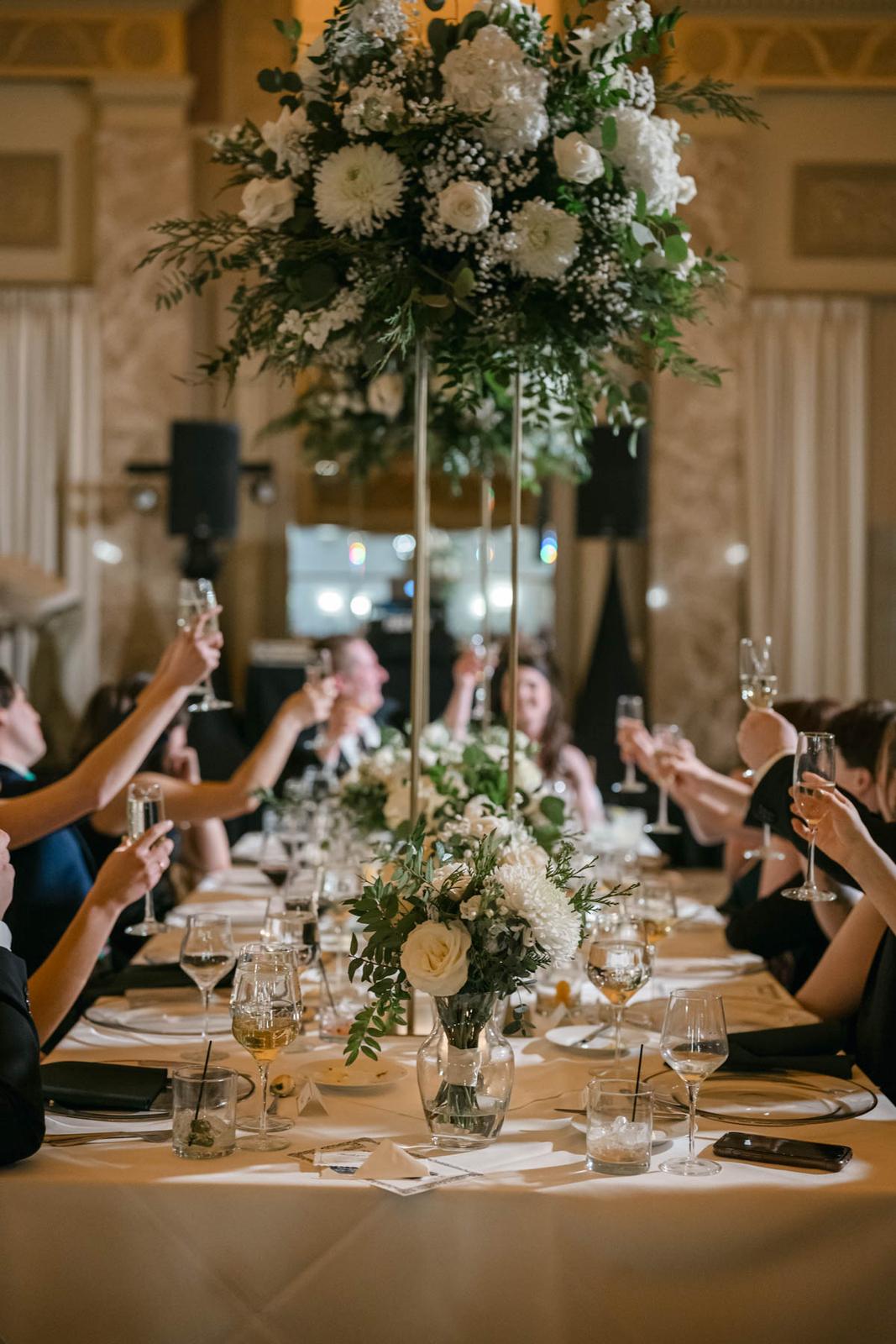 Tall and low white floral centerpieces with candlelight at a wedding reception at The Coronado