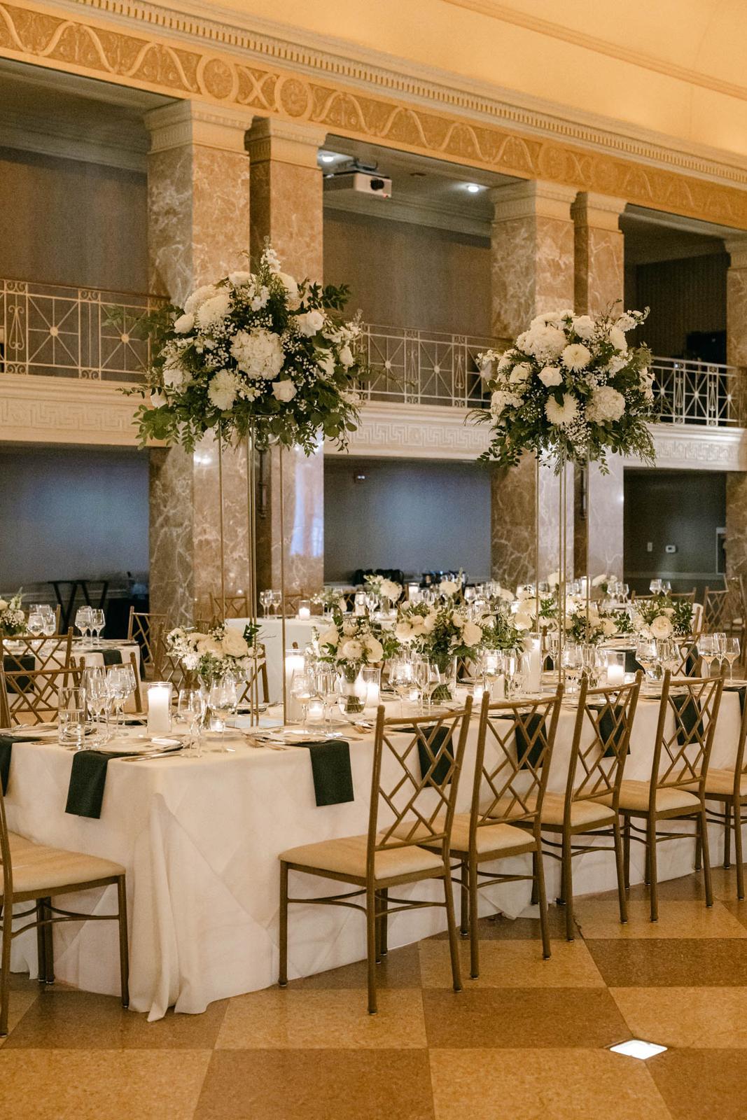 Tall white floral centerpieces on gold stands at a wedding reception at The Coronado in St. Louis
