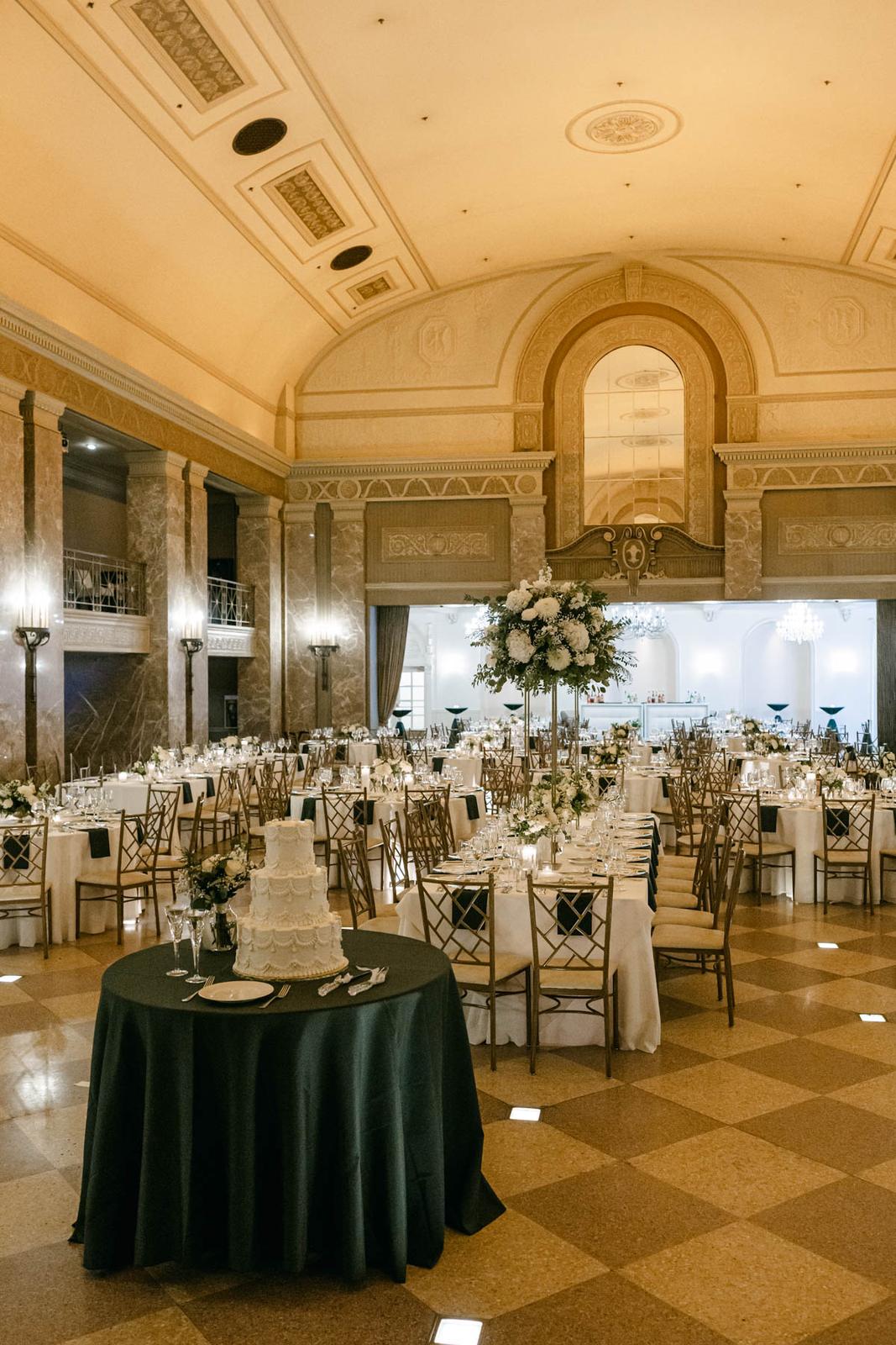 White wedding centerpieces and gold chairs in the ballroom at The Coronado in St. Louis