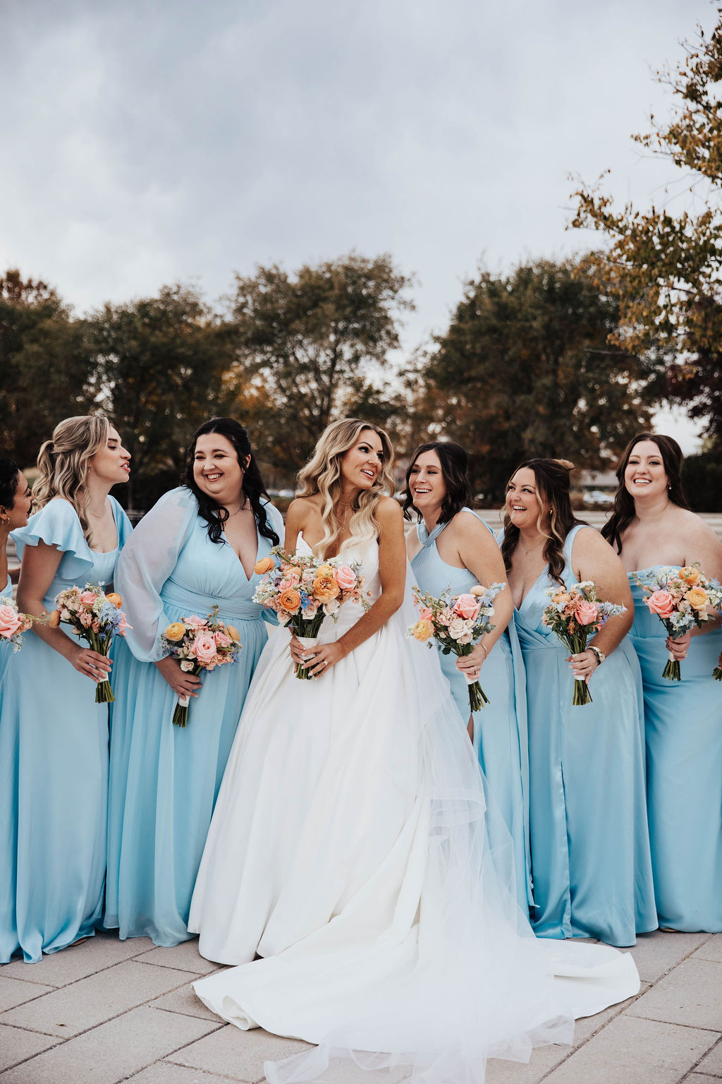 Wedding bouquet featuring peach ranunculus, coral pink, light blue and white flowers