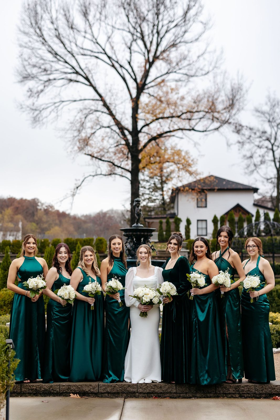 Bridesmaids in emerald green dresses carrying ivory wedding bouquets