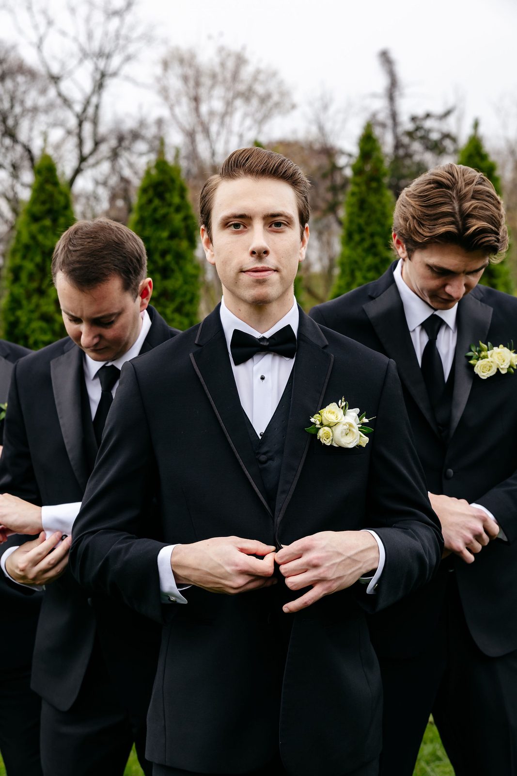 Men wearing ivory flower pocket boutonnieres with dark suits