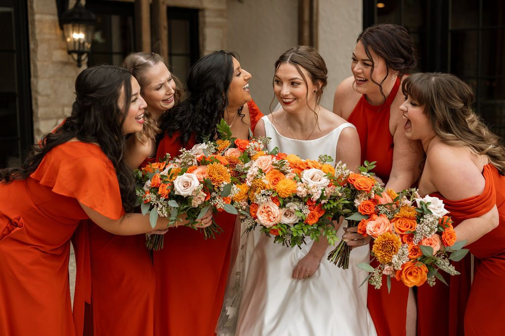 Bridal party holding colorful fall wedding bouquets with orange dahlias