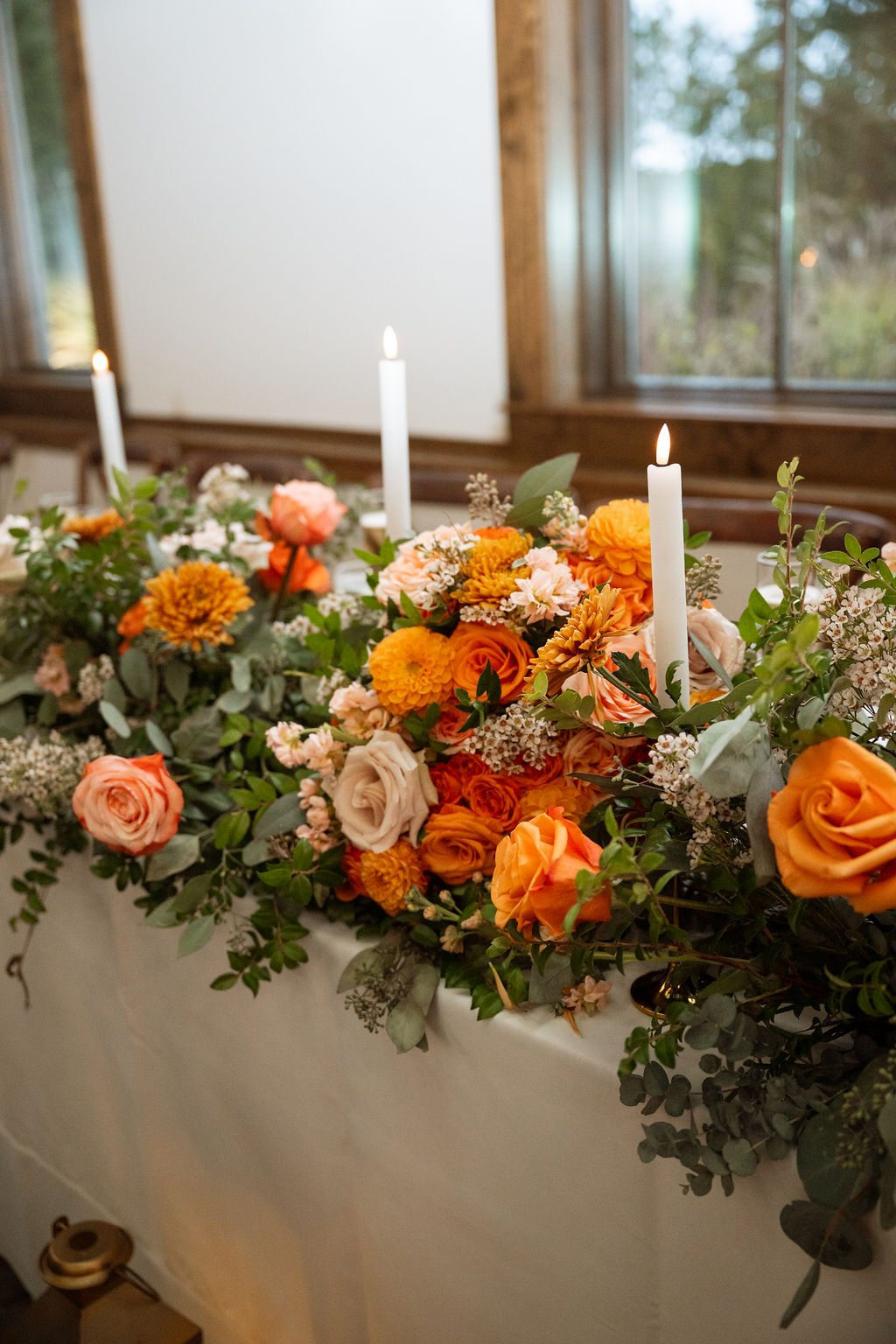 Terracotta, peach and orange wedding flowers in the head table arrangement at Silver Oaks Chateau